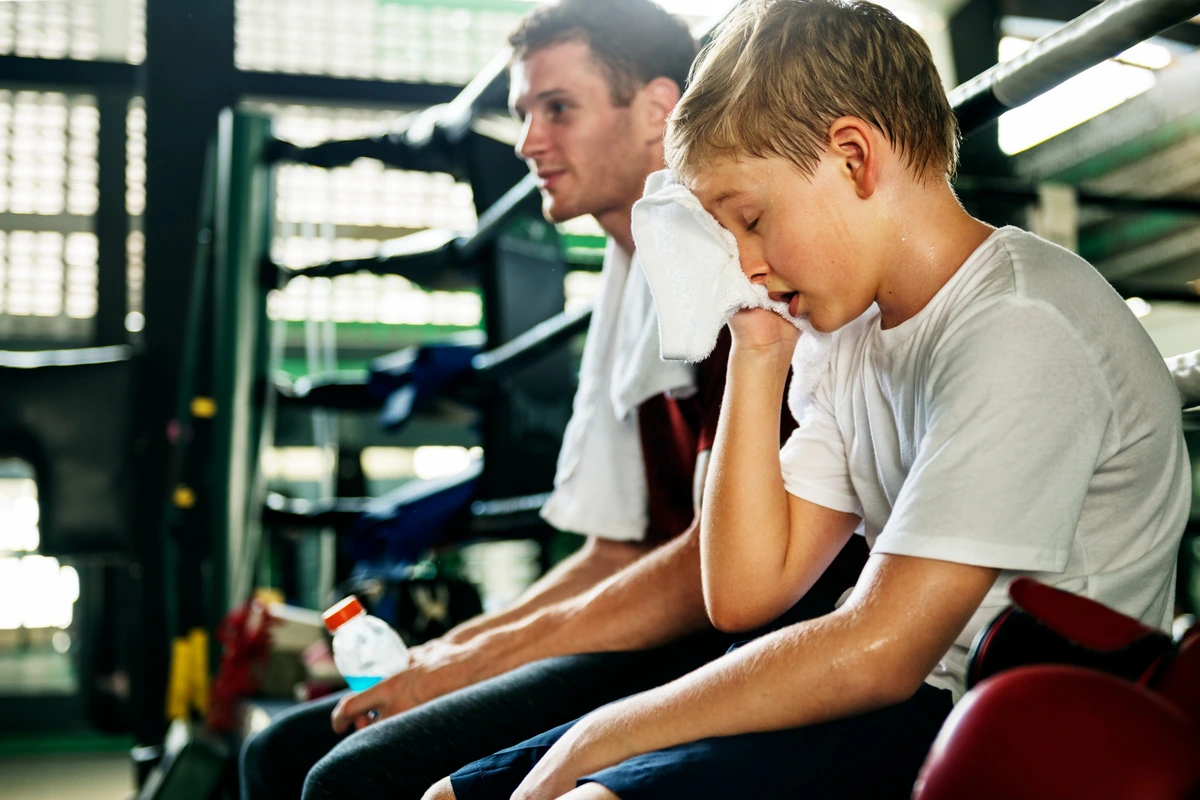 A boy resting after sports practice next to an adult coach
