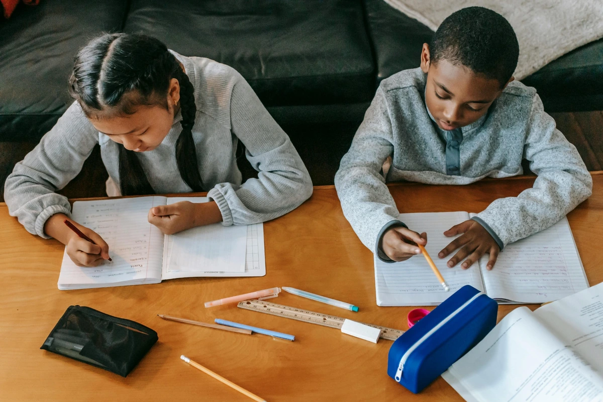 Children working on a task together at a table as an example of small steps in learning