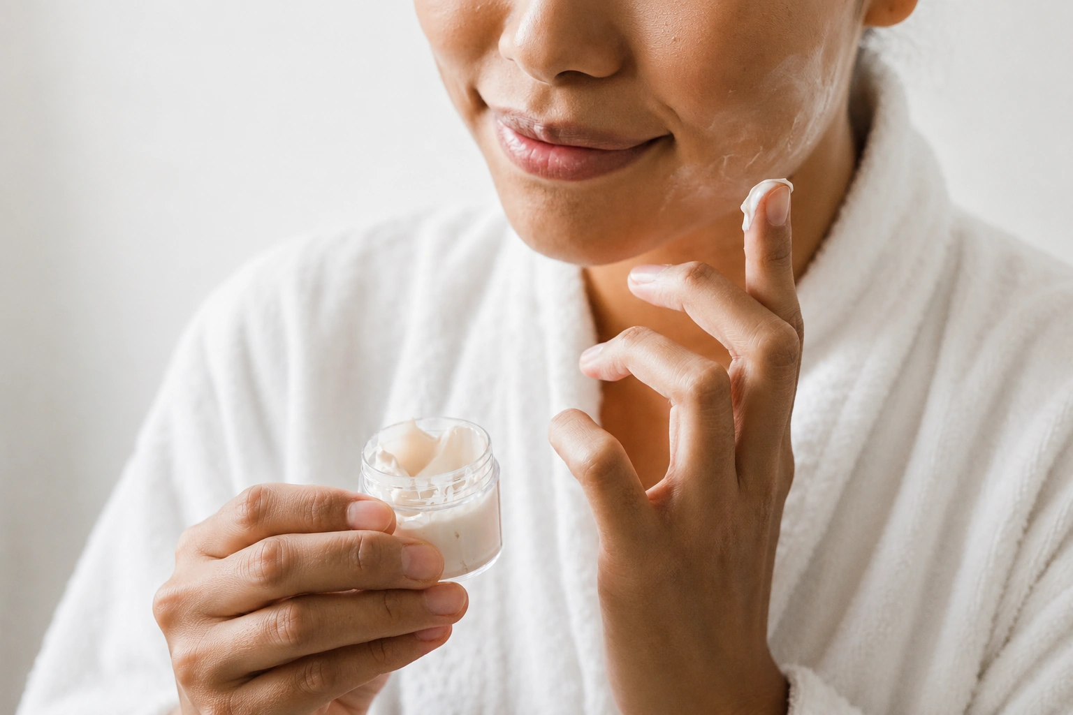 A woman scoops a rich cream out of a jar. Sensory experiences when using cosmetics.