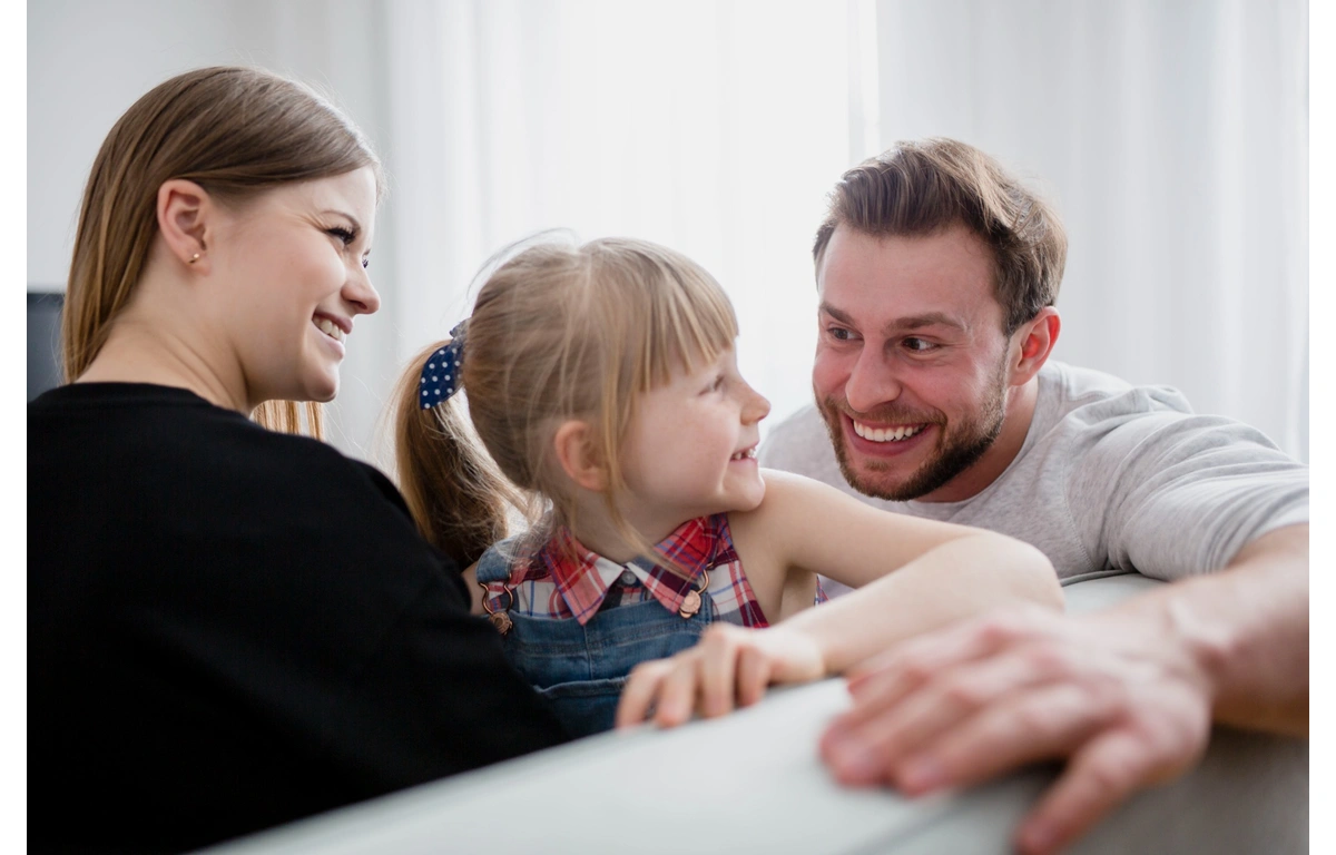 Rodzice i dziecko łączą się spojrzeniem i uśmiechem — żywa emocjonalna wymiana, która rozwija empatię i samoregulację