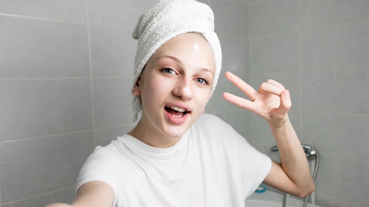 Nastolatka nakłada krem podczas prostego zabiegu pielęgnacyjnego dla skóry skłonnej do trądziku