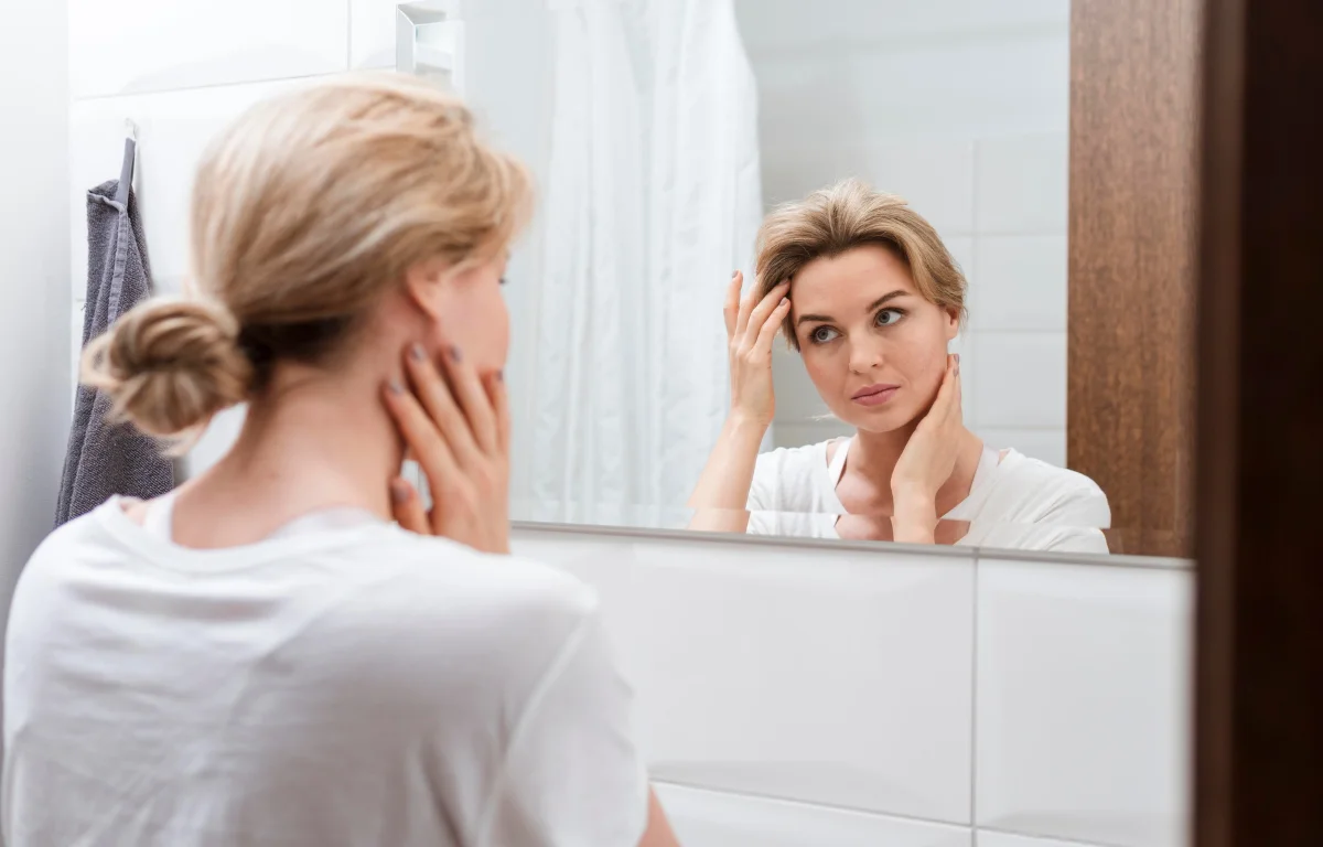 Woman looking at herself in the mirror during a self-care routine affected by digital fatigue