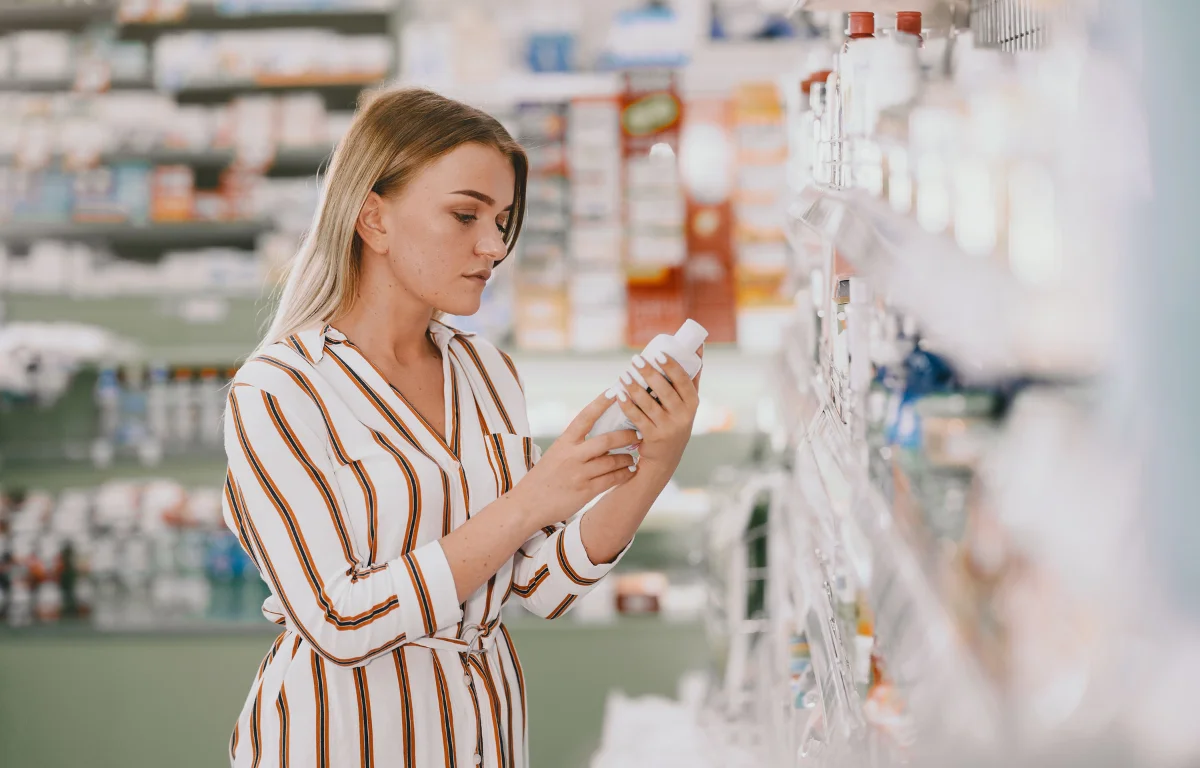 Woman in a store reading skincare ingredients, choosing long-term stability over anti-age results