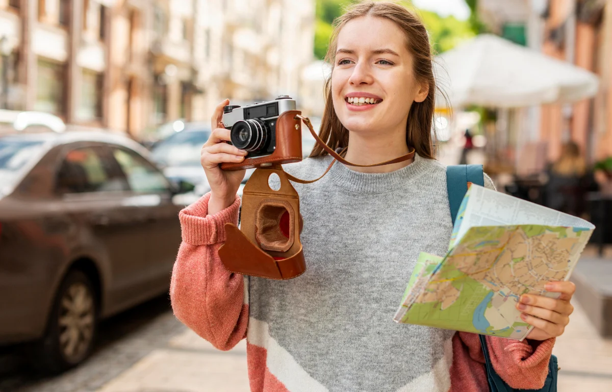 Young woman with camera and map on a city street reflecting modern travel trends